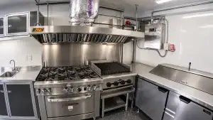 Clean stainless steel commercial kitchen exhaust hood over gas range and charbroiler for professional hood cleaning and NFPA 96 maintenance