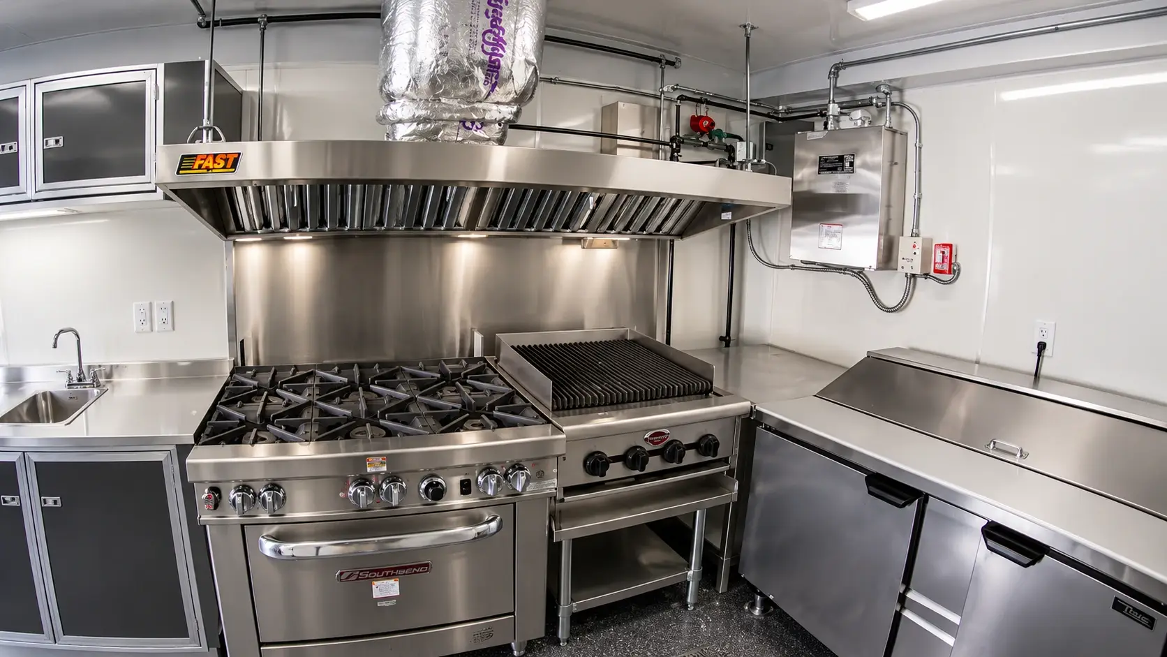Clean stainless steel commercial kitchen exhaust hood over gas range and charbroiler for professional hood cleaning and NFPA 96 maintenance